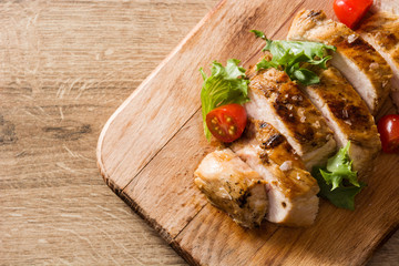 Grilled chicken breast with vegetables on wooden table. Top view. Copy space