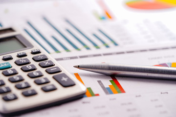 Calculator and pen on charts and graphs spreadsheet paper. Finance, Account, Statistics, Analytic research data and Business company meeting concept.