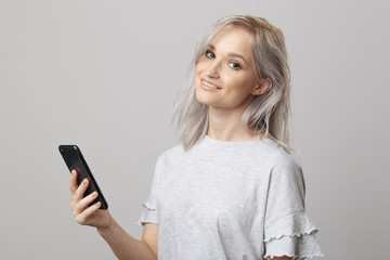 Naklejka premium Happy blond woman in studio holding phone