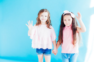 two little girls girlfriends together on blue background