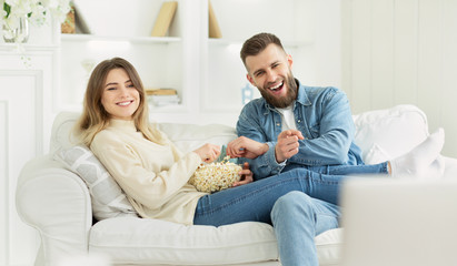 Fototapeta na wymiar Happy millennial couple watching tv with popcorn