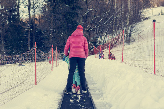 Rear view of mother helping her child on cki conveyor belt.