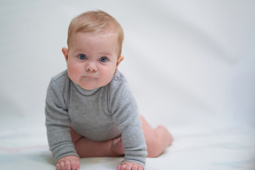 Fototapeta premium a six-month-old baby learns to crawl. emotional portrait of a child