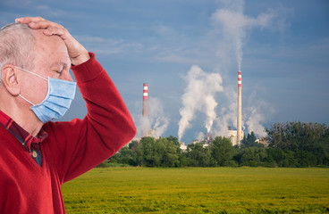  Senior man against the background of pipes polluting an atmosphere
