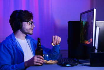 Gamer having break and drinking beer with chips