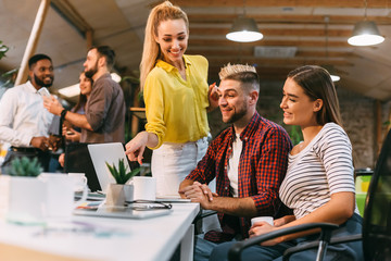 Young colleagues analyzing data on laptop in office
