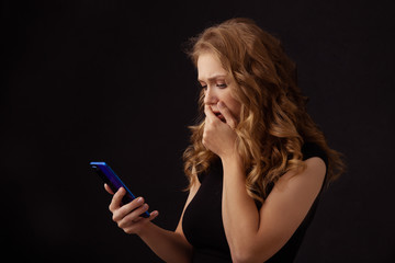 Obraz premium Scared annoyed girl watching phone and closing her mouth