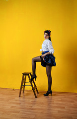 pin-up girl in a blue skirt on a chair on a yellow background