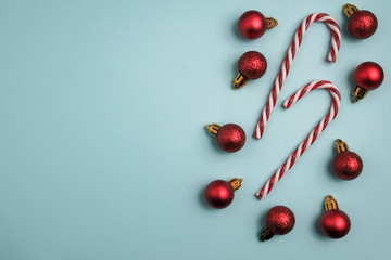 Christmas winter composition. Red balls with candy canes on blue background. Top view, flat lay
