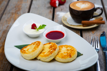 Traditional breakfast with coffee and cheesecakes, cottage cheese pancakes on a plate with syrup and jam.