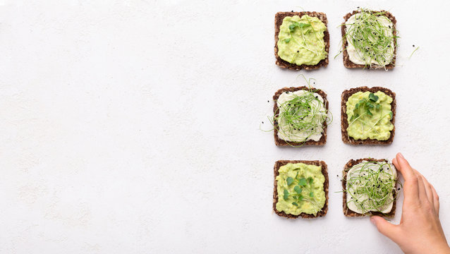 Girl taking vegan toasts with avocado, tofu and microgreens