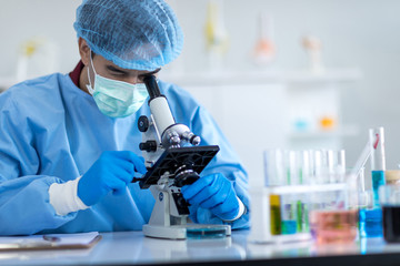 Asian scientists wear protective clothing looking for microscopes while doing medical research in a...
