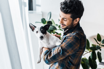 smiling and handsome bi-racial man holding Jack Russell Terrier