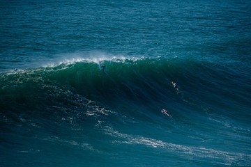 Surfers sailing in the Atlantic Ocean near the Nazare municipality in Portugal