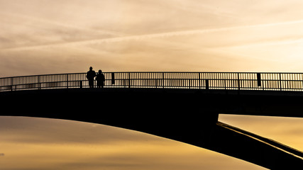 Two people looking from a bridge in to the distance