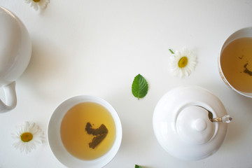 Set with green tea, cups and kettle, mint leaves and chamomile flowers, with free space for text, long wide banner
