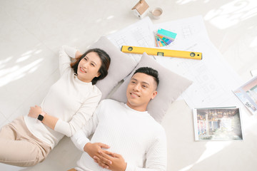 A young couple lying on the floor of their new home, think about their new interior decoration