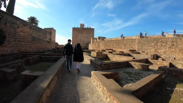 Couple walking along the Alcazaba towards Torre de la Vela (Candle tower) in la Alhambra. Granada, Andalusia, Spain..