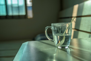 a close up shot on a glass cup on the table, with blurred background of sunset twilight through the window