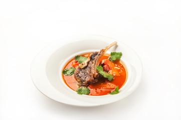 Vegetable soup with tomatoes in a restaurant close-up. Lamb soup on bone noodles on a white plate and copy space.