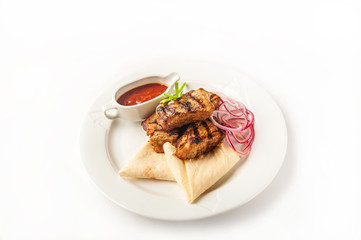 Skewers with sauce in a restaurant close-up. Skewers with onions and pita bread on a white plate and copy space.