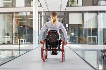 Frau im Rollstuhl im behindertengerechten Bürohaus - obrazy, fototapety, plakaty