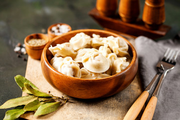 Traditional russian pelmeni, ravioli, dumplings with meat on concrete background. Russian food and russian kitchen concept. Selective focus