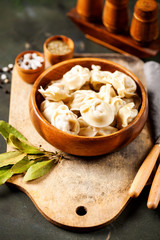 Traditional russian pelmeni, ravioli, dumplings with meat on concrete background. Russian food and russian kitchen concept. Selective focus
