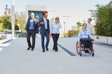 Business Team unterwegs mit Kollegin im Rollstuhl