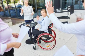 Business Team Kollegen winken Frau im Rollstuhl