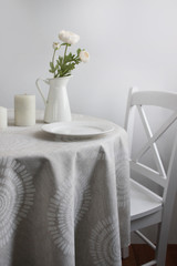 a table with plates and a flower, in bright colors. round table with a light tablecloth on a white background.