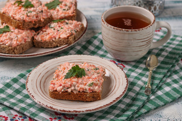 Homemade sandwiches with crab sticks, cheese and carrots on a plate on a checkered tablecloth, horizontal orientation