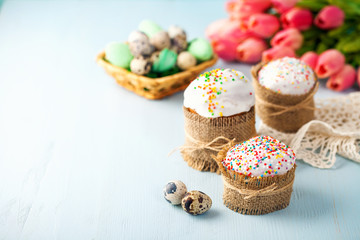 Easter orthodox sweet cakes, kulich and colorful quail eggs with pink tulips. Holidays Easter concept. Selective focus