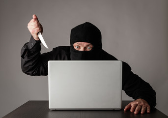 Hacker in mask using a laptop.