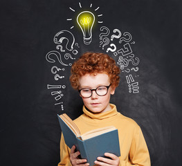 Child reading on blackboard background with lightbulb