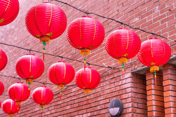 Fototapeta na wymiar Beautiful round red lantern hanging on old traditional street, concept of Chinese lunar new year festival, close up. The undering word means blessing.