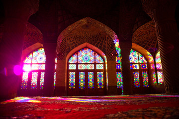 Fototapeta na wymiar Shiraz, Iran. The sunlit stained-glass windows in the morning sun in the Nasir-ol-molk Mosque. Interior view.