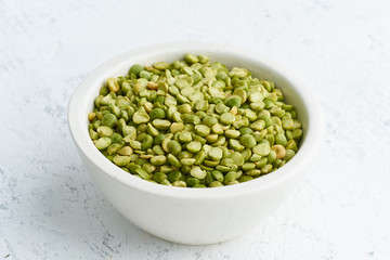 Green peas in white bowl on white background. Dried cereals in cup, vegan food. Side view, close up.