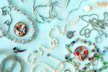 Jewelry on a textured background. Accessories in the form of jewelry and bijouterie for women's fashion. Pearl beads, pendants, bracelets on a turquoise background.