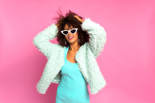Beautiful african american young girl smiling and posing in stylish dress.  Studio shot of joyful Afro American woman laughs sincerely, feels relaxed, dances while listens favourite music, wears coat.