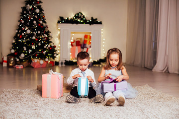 Fototapeta na wymiar little boy and girl open Christmas presents new year winter Christmas tree