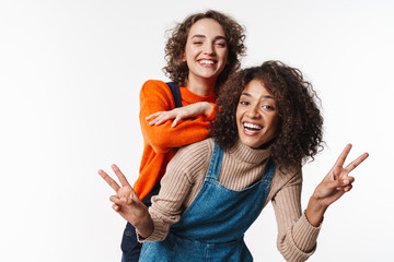 Portrait of joyful multinational women gesturing peace sign