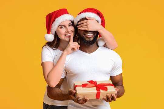 Affectionate woman in Santa hat prepared Christmas present to her boyfriend