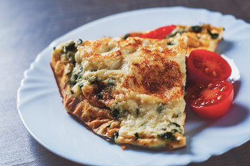 omelet with spinach in white plate on wooden table background
