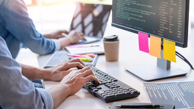 Young startup Programmers Sitting At Desks Working On Computers screen for Developing programming and coding to find solution to problem on New Application.
