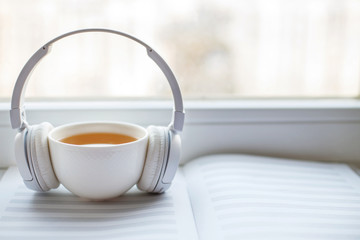 white headphones with a cup of tea on the window