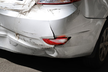 Close-up wrecked rear bumper and tail lights of new modern grey car after vehicle accident on road...