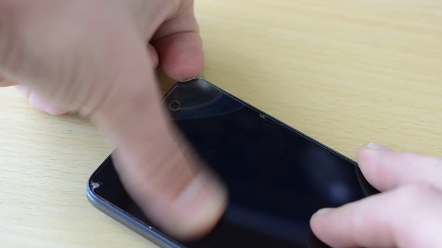 The master removes the protective glass from the smartphone, the glass cracks and breaks