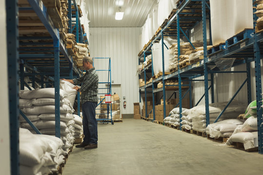 Man adjusting grain sack on shelf