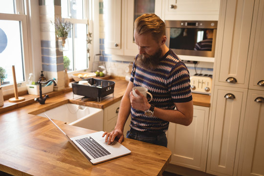 Man having coffee while using a laptop